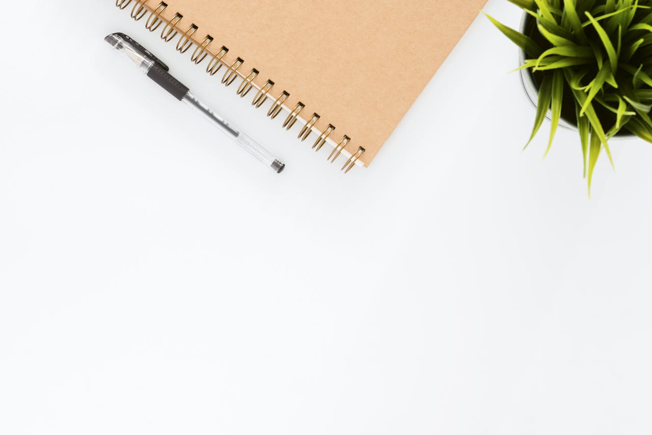 creative Minimalist stationery setup with a spiral notebook and pen on a clean white desk.