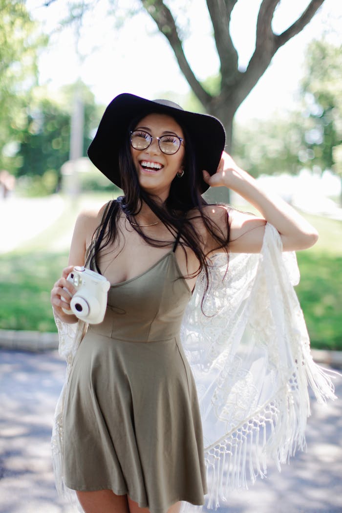digital Cheerful woman in a boho dress with a camera enjoying a sunny day outdoors.
